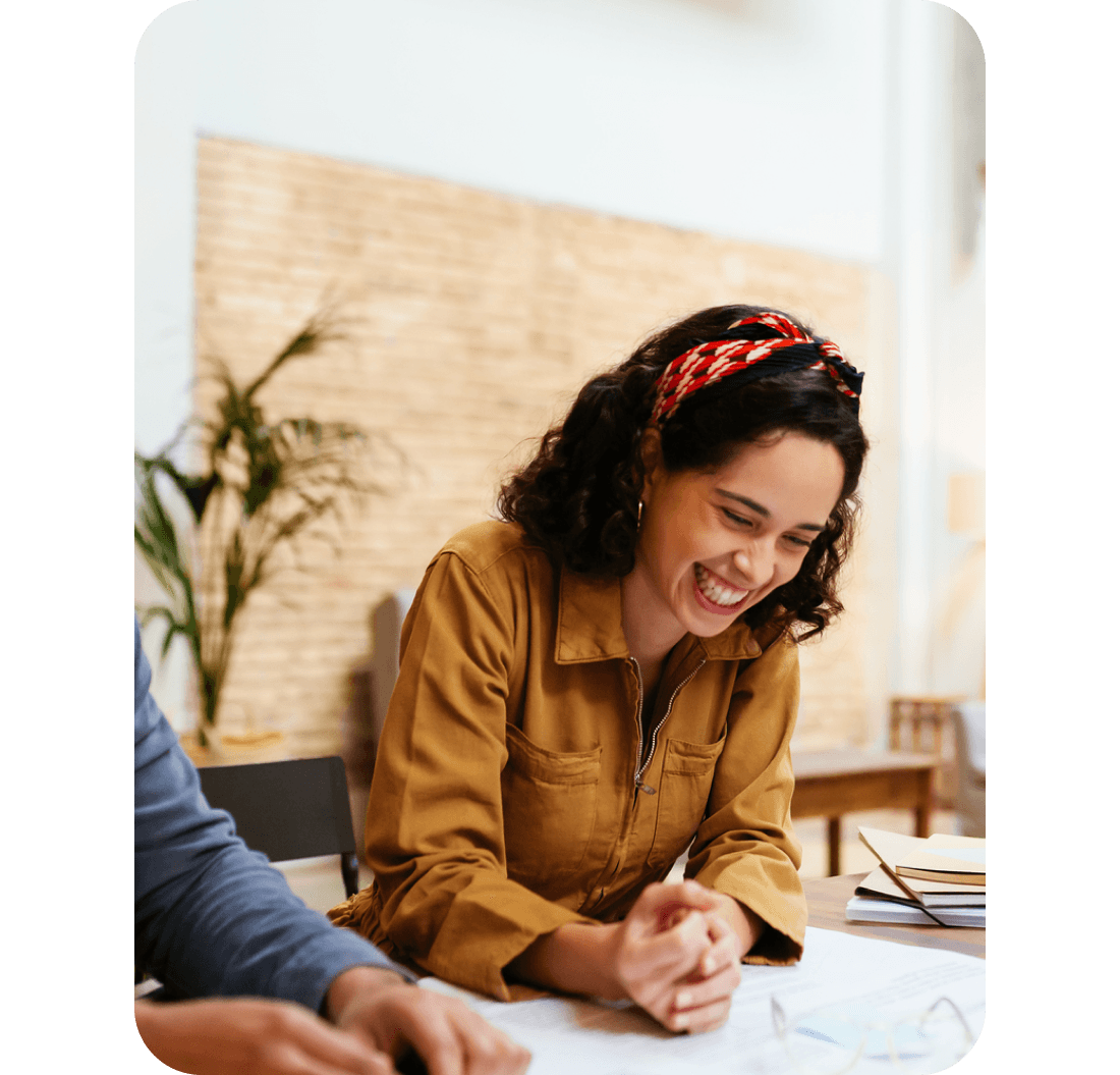 A photo of a woman smiling while sat at a desk