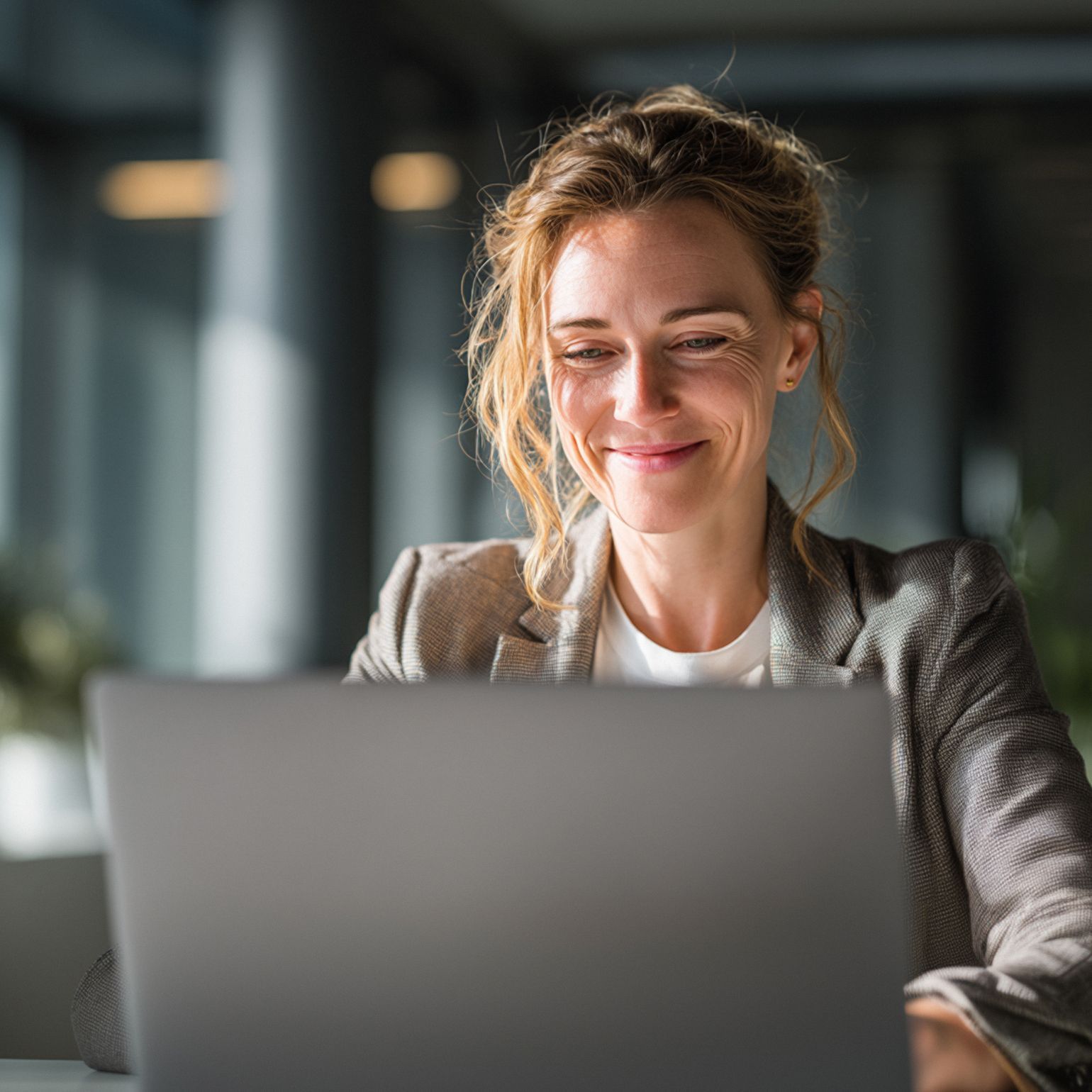 A photo of a man sat down and smiling in front of a laptop