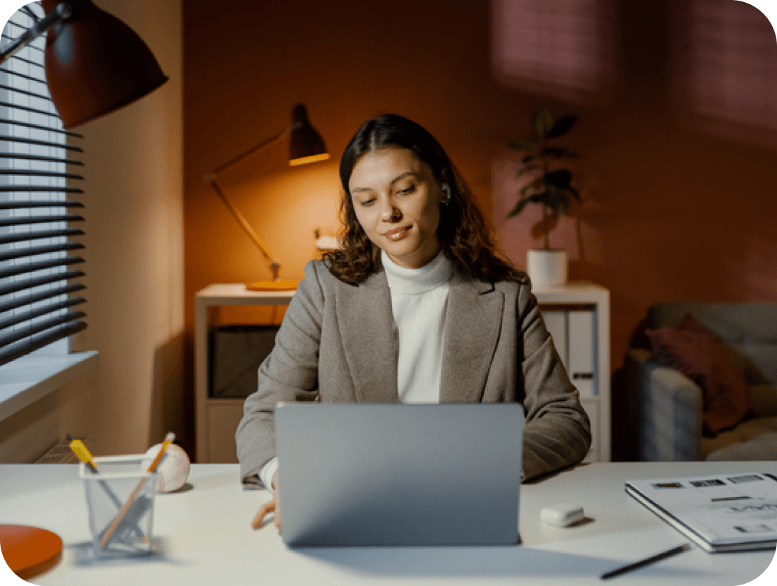 A photo of a woman looking down at a laptop in a home office environment