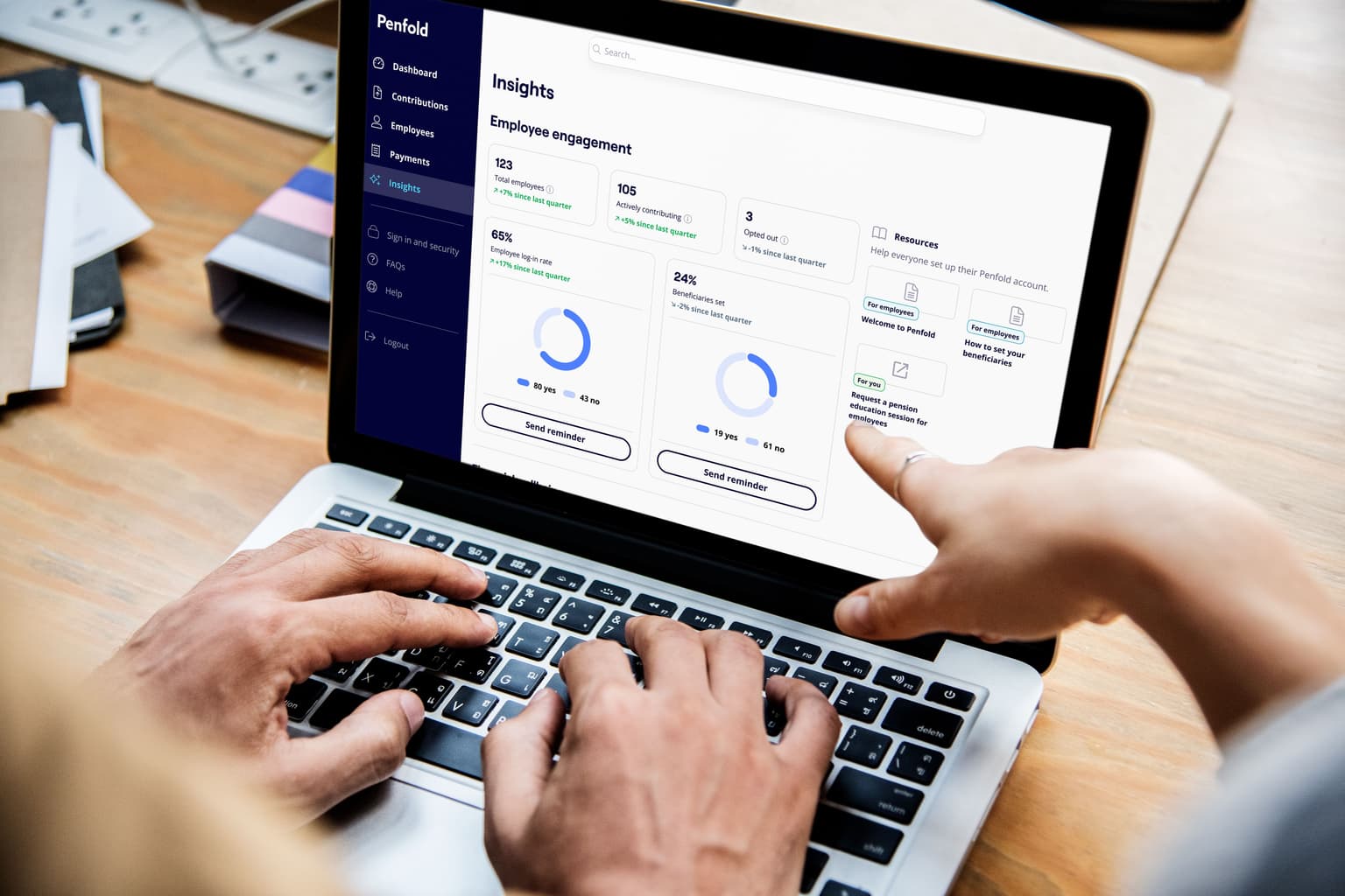 Hands typing on a laptop displaying the Penfold Insights employee engagement dashboard, with another hand pointing at the screen.