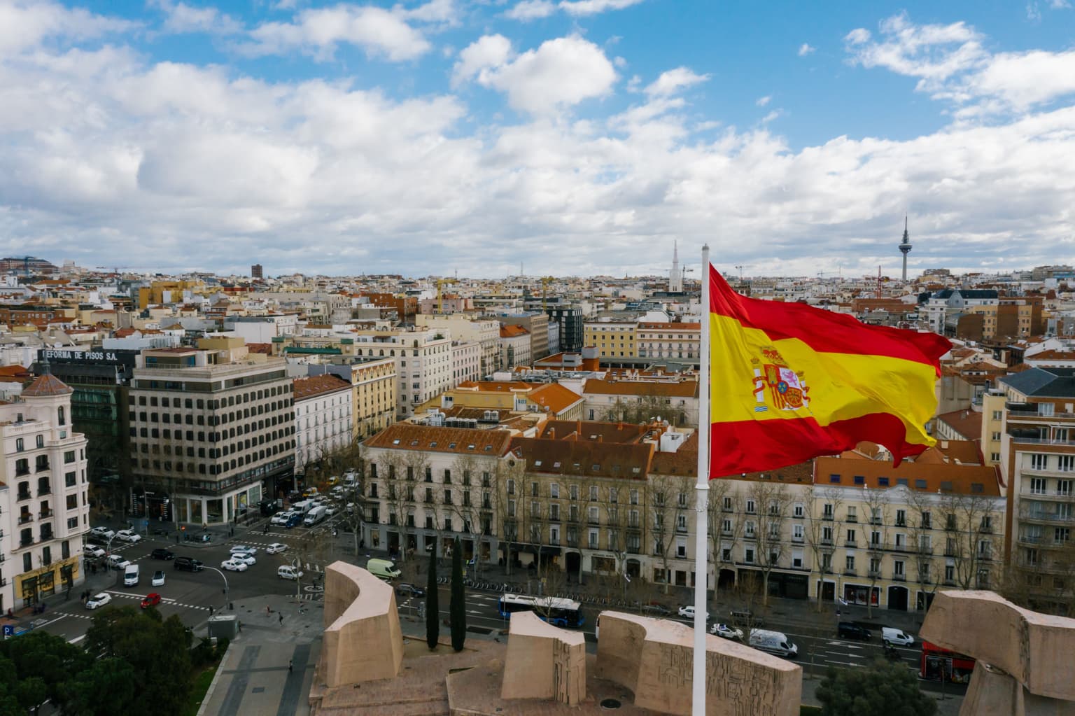 city scape of spain with a spanish flag in the foreground