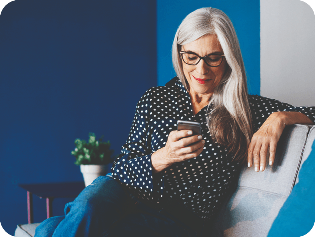 A photo of a woman looking at a phone while sat on a sofa