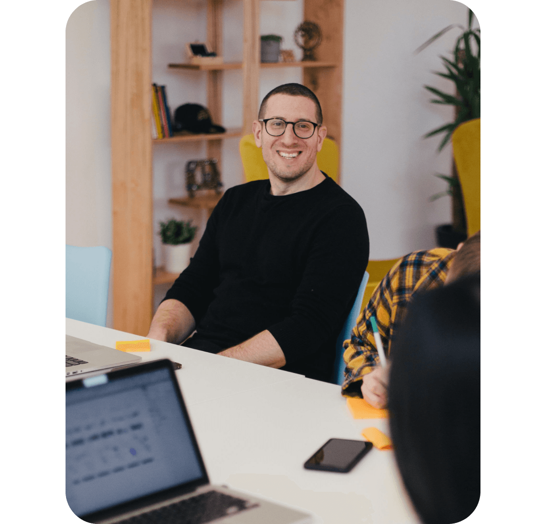 A photo of a man smiling while sat at a desk
