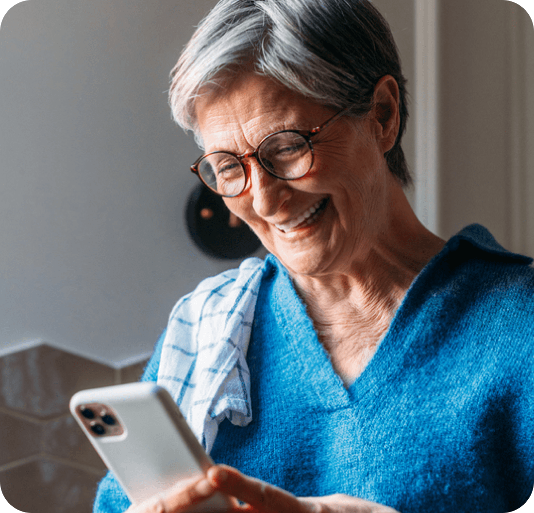 A photo of a woman smiling and looking down at her phone